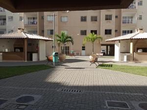 a courtyard with benches and umbrellas in front of a building at O melhor e + aconchegante AP de SPA (custo/benefício) in São Pedro da Aldeia
