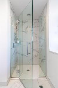 eine Dusche mit Marmorwänden und einer Glastür in der Unterkunft Enchanted Escape 2 bed 2 bath CBD in Christchurch
