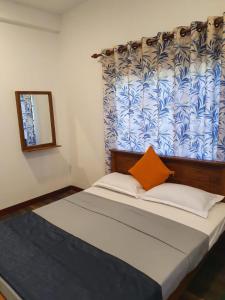 Schlafzimmer mit einem Bett mit orangefarbenem Kissen in der Unterkunft Belihull Vila in Nuwara Eliya