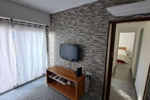 uma sala de estar com uma televisão e uma parede de tijolos em Departamento amplio y luminoso em Buenos Aires
