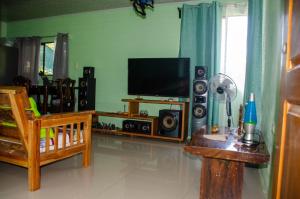 sala de estar con TV de pantalla plana y mesa en Natural Harmony Cabin, en Puerto Jiménez