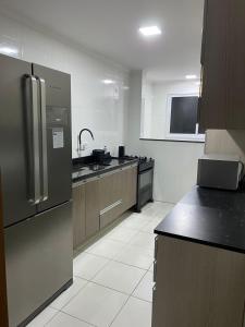 eine Küche mit Edelstahlkühlschrank und Schränken in der Unterkunft Praia Grande - Condomínio Grygor in Praia Grande + 4 Fotos