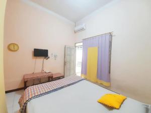 een slaapkamer met een groot bed en een televisie bij Homestay at Homy House by ecommerceloka in Jomblang