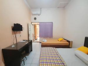 een kamer met 2 bedden en een bureau. bij Homestay at Homy House by ecommerceloka in Jomblang