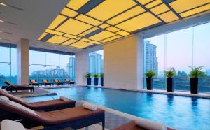 a large swimming pool with chairs and tables in a building at Four Points by Sheraton Guangzhou, Dongpu in Guangzhou