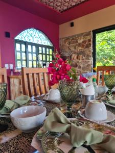 a table with plates and bowls and flowers on it at Pousada Lajedo in Serra de São Bento