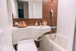a bathroom with a sink and a toilet and a mirror at R Hotel Honmachi in Osaka