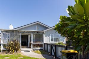 a house with a screened in porch with a fence at Tui nest in Whangamata