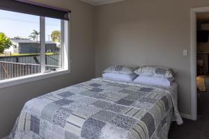 a bedroom with a bed and a large window at Tui nest in Whangamata