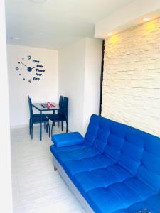 ein blaues Sofa in einem Zimmer mit einem Tisch und einer Uhr in der Unterkunft Apartamento Ibague in Ibagué