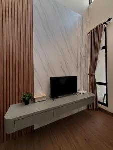 ein Wohnzimmer mit einem TV auf einer Bank in der Unterkunft RT House Cozy Homestay 2BR Podomoro Golf View in Taladjurg-udik