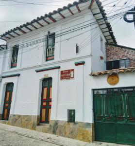 un edificio blanco con puertas verdes en una calle en Hostal Casa del Frailejón - Café en Monguí