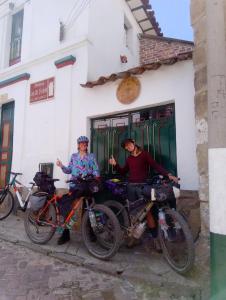deux personnes avec leurs vélos devant un bâtiment dans l'établissement Hostal Casa del Frailejón - Café, à Monguí