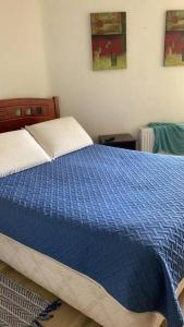 Schlafzimmer mit einem Bett mit blauer Decke in der Unterkunft Departamento San Alfonso del mar in San Antonio