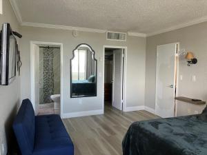 a bedroom with a blue couch and a mirror at Oceanview on SAND located in Ocean Manor Resort Fort Lauderdale Beach 2 bed 2 bath spacious corner unit partial ocean view in Fort Lauderdale