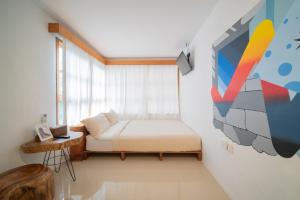 1 dormitorio con 1 cama y una pintura en la pared en Danka Vacation Home en Seribu