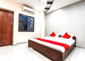 een slaapkamer met een bed met rode kussens en een raam bij OYO Flagship Sathya Inn in Warangal