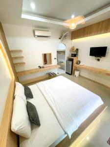 a bedroom with a large white bed and a tv at Dara Homestay in Ko Kood