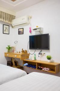 a bedroom with two beds and a tv on the wall at West Lake Hefang Street Metro Exit B&B in Hangzhou