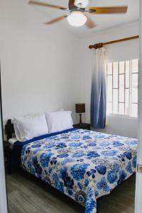een slaapkamer met een blauw en wit bed en een plafondventilator bij Hermosa Paradise Mins From Beach in Playa Hermosa