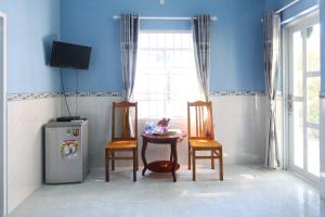 um quarto com uma mesa, 2 cadeiras e um frigorífico em Đức Anh Bungalow em Duong Dong