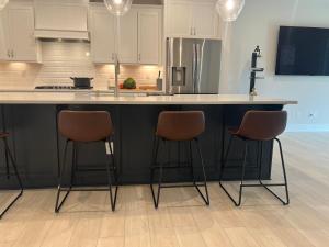 a kitchen with a counter with three bar stools at Charlotte Comfort Haven in Charlotte