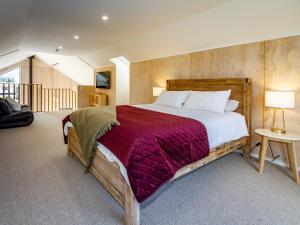 a bedroom with a large bed with a red blanket at Viewtopia - Ohakune Holiday Home in Ohakune
