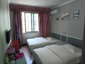 a hotel room with two beds and a television at Dihao Hostel North Railway Station in Guilin