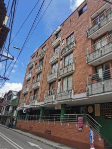 a red brick building with balconies on a city street at Acogedor Apto Parque Sabaneta in Sabaneta