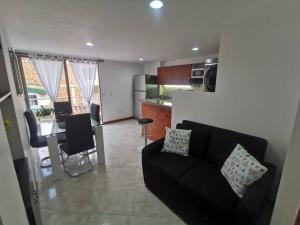 a living room with a black couch and a kitchen at Acogedor Apto Parque Sabaneta in Sabaneta