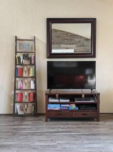 a living room with a flat screen tv and a book shelf at Corner Lake Getaway in Bella Vista
