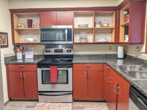 a kitchen with red cabinets and a stove and a microwave at Corner Lake Getaway in Bella Vista