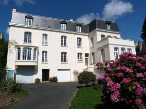 una gran casa blanca con flores delante en Vintage holiday apartment on the 1st floor of an elegant mansion - Coutances, en Coutances