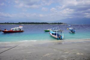 Trois bateaux dans l'eau sur une plage dans l'établissement Kiayazo ViBES Inn, à Gili Trawangan