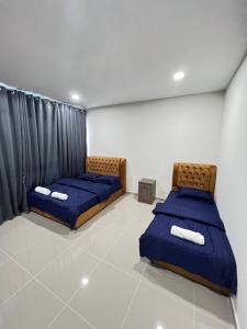 - 2 lits dans une chambre avec des draps bleus dans l'établissement TAMU HOMESTAY Alam Mutiara, à Kuala Terengganu