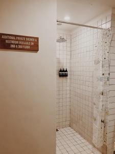 een badkamer met een douche met een bord aan de muur bij Kos One Hostel in Canggu