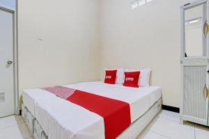 Un dormitorio con una cama con almohadas rojas. en OYO Life 93034 Ayri Home, en Salatiga