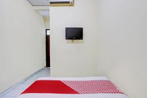 a room with a bed and a tv on a wall at OYO Life 93034 Ayri Home in Salatiga