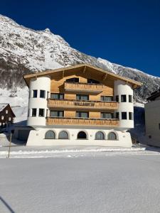 a building in the snow in front of a mountain at Garni Apart Wallamotta Silvretta Card Premium Betrieb in Galtür