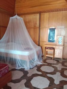 a bedroom with a bed with a mosquito net at Lestari Cottages in Kododa