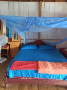 a bedroom with a bed with a blue canopy at Lestari Cottages in Kododa