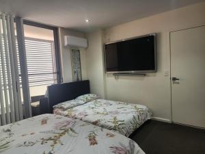 a hotel room with two beds and a flat screen tv at Parramatta Shared Apartment in Sydney
