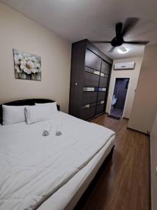 a bedroom with a white bed with a ceiling fan at Hijauan Homestay Shah Alam in Shah Alam