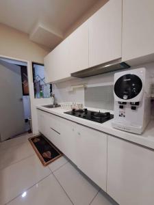 a kitchen with white cabinets and a stove top oven at Hijauan Homestay Shah Alam in Shah Alam