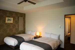 2 camas en una habitación de hotel con lámpara en ホテルコンドミニアム土花土花, en Onna