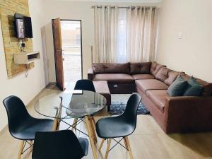 uma sala de estar com um sofá e uma mesa de vidro e cadeiras em Sekgome Resort em Joanesburgo