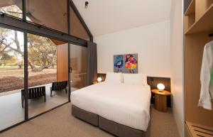 a bedroom with a white bed and a large window at Par Five Shacks in Berri