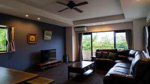 恩納村にあるHotel Condominium DOKADOKAのリビングルーム(革張りのソファ、テレビ付)