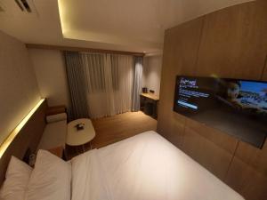 a hotel room with a bed and a flat screen tv at Adena Hotel in Busan