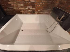 a large white bath tub in a room with a brick wall at Adena Hotel in Busan